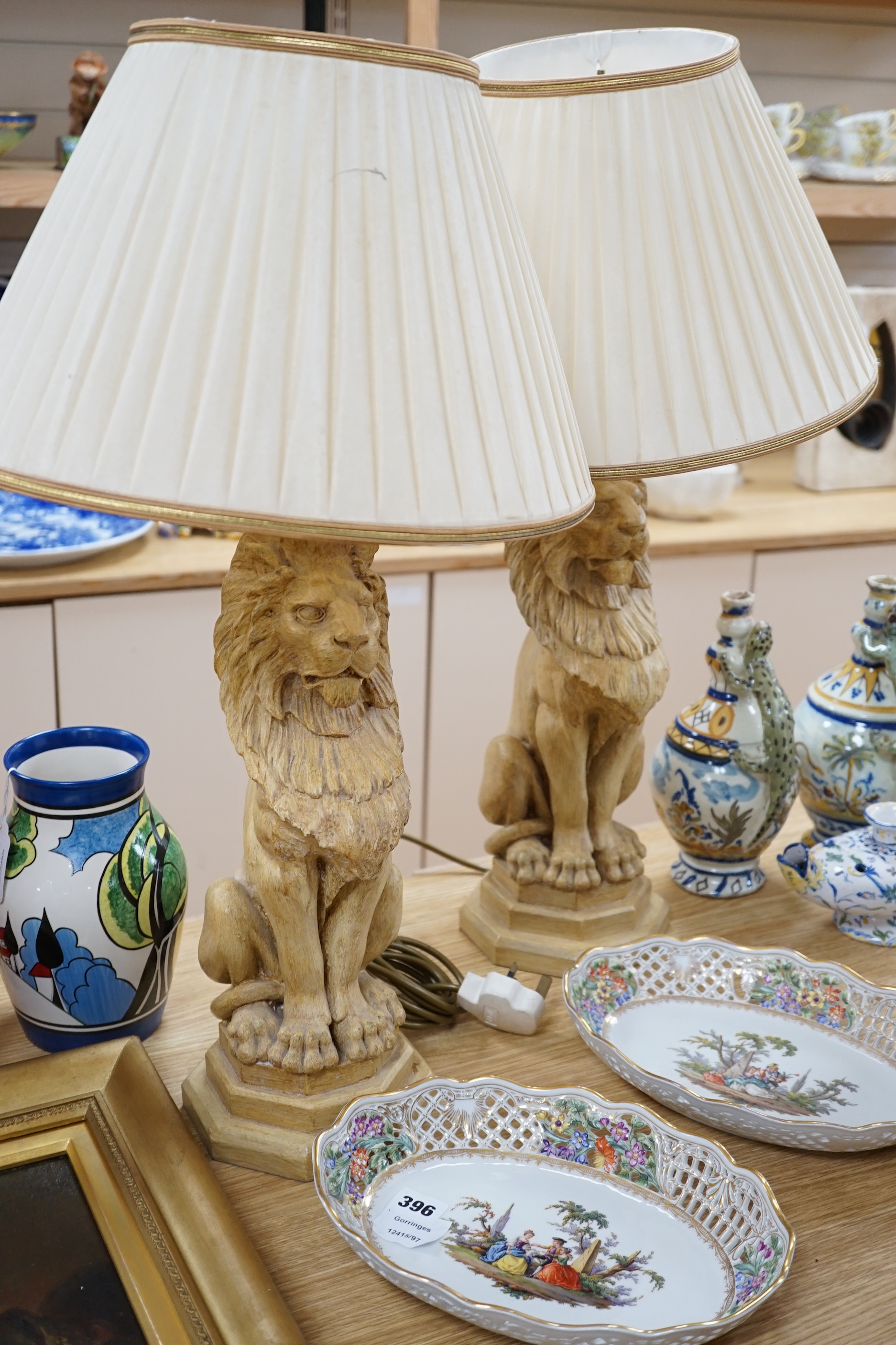 A pair of Thomas Blakemore composition lion lamps with cream shades, 64cm